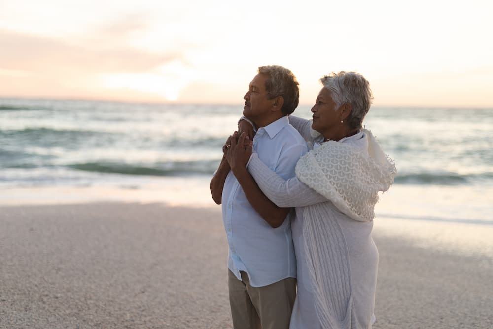 senior couple on beach in front of sunset