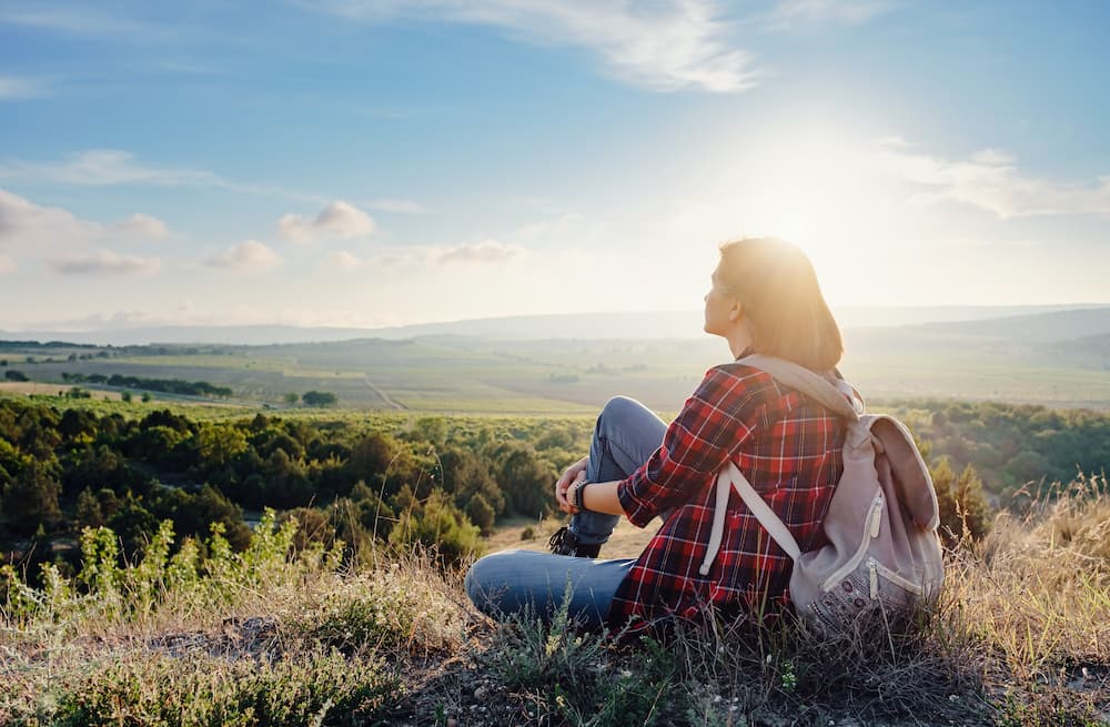 young woman enjoys sunset above countryside uses Aero-Wrap compression for improved health and recovery of leg swelling